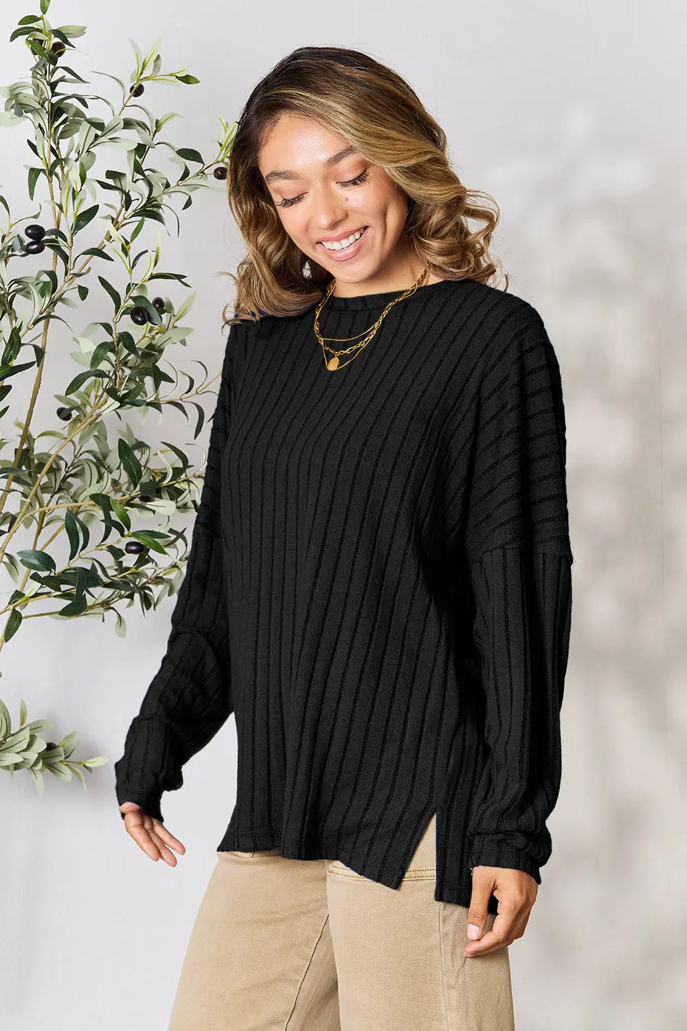 Trendsi black ribbed knit sweater with long sleeves and side slits worn by smiling woman