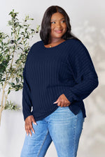 Plus size woman wearing navy blue ribbed knit long sleeve top paired with light wash jeans