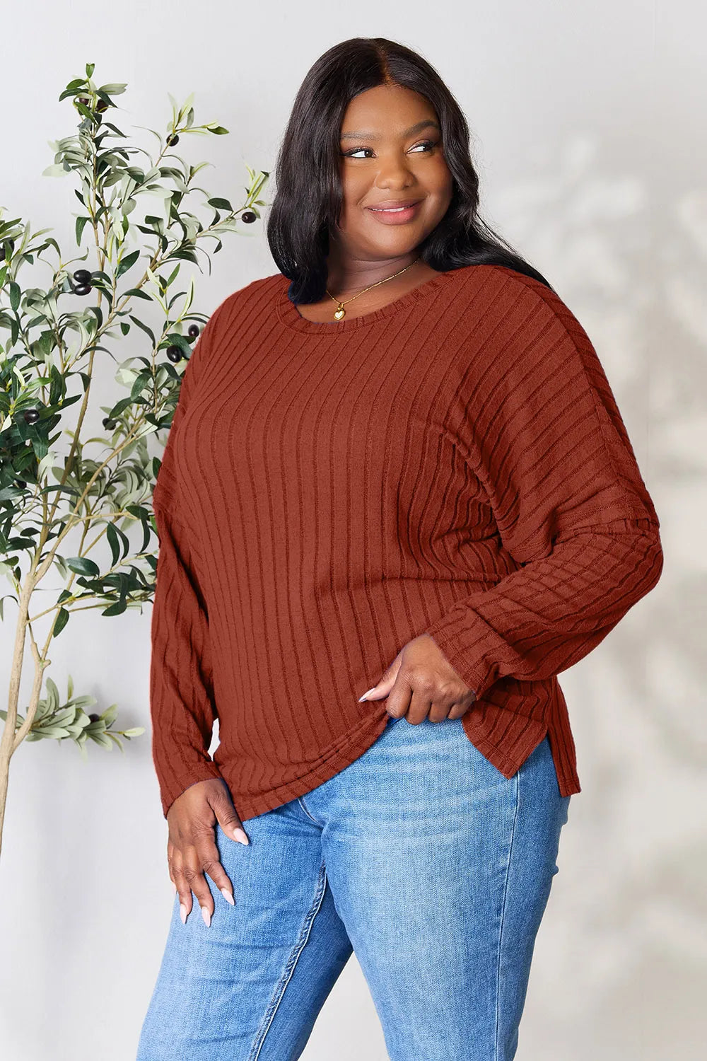 Plus size woman wearing a brown ribbed knit long sleeve top paired with blue jeans