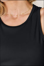 Close-up of a black sleeveless top tank tops worn by a woman with a delicate gold necklace