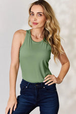 Woman wearing olive green sleeveless top tank tops paired with dark blue jeans